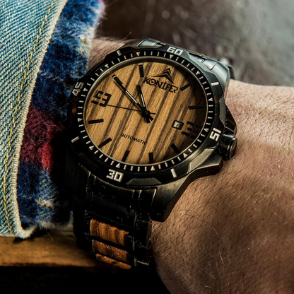 Montre en metal noir et en bois zebre a cadran rond. Sur poignet