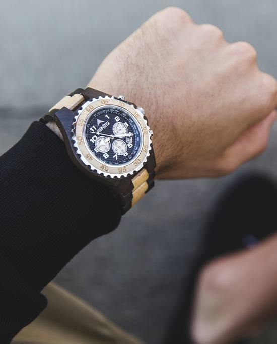 Montre en bois marron et beige a cadran rond. Sur poignet